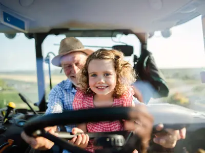 Image of Senior and Child on Tractor Smiling