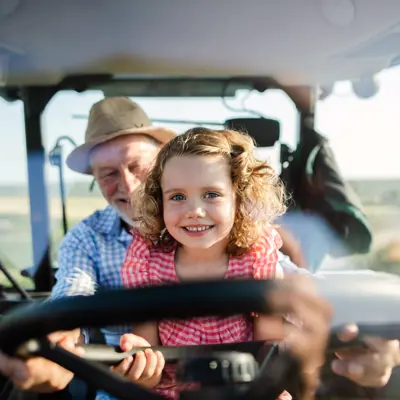 Image of Senior and Child on Tractor Smiling